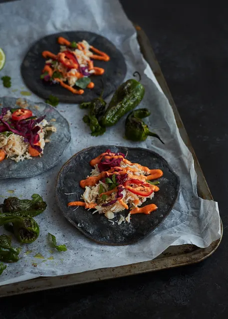 Crab tacos on blue corn tortillas with blistered padrón peppers