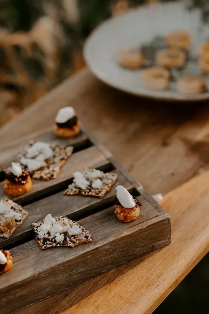 Seeded crackers and goat cheese bites on a wooden tray