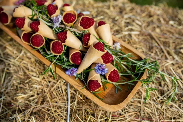 Raspberry cones on rosemary in a wooden tray