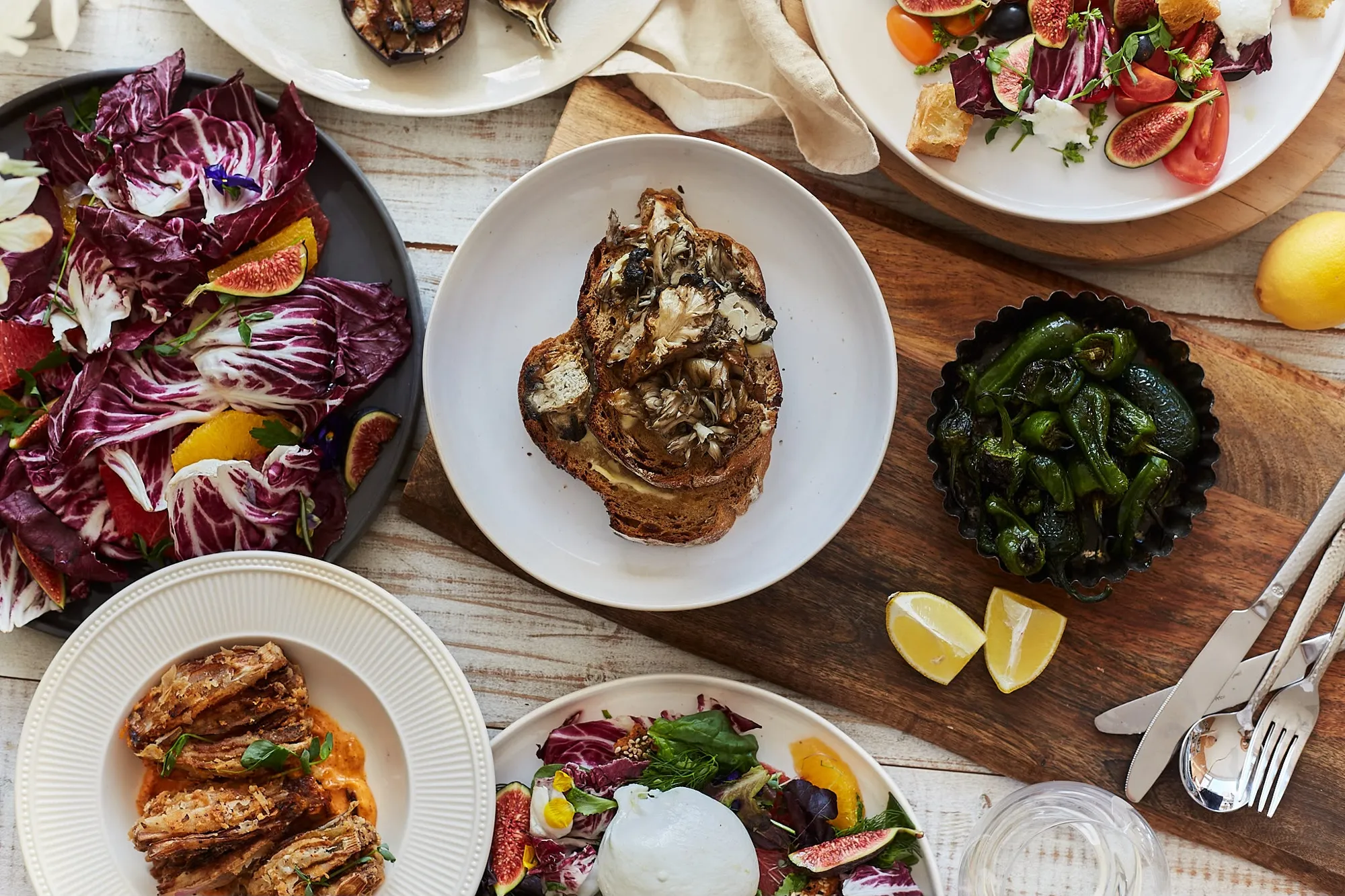 A long table of radicchio and fig salad, mushroom toast, padrón peppers and burrata